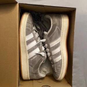 Adidas campus - Gråa adidas campus 00s i bra skick förutom två små hål i hälen men inget som syns när de används, org Låda och extra skosnören medföljer, skriv vid minsta fråga eller fundering🔥👍