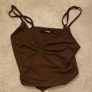 Brun linnetopp från BikBok - Säljer en snygg brun linnetopp från BikBok i storlek XS. Toppen har smala axelband och en enkel design som passar perfekt till både vardag och fest. Materialet känns mjukt och bekvämt mot huden. Perfekt för sommardagar eller som ett lager under en jacka.