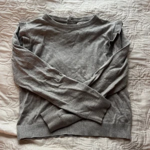 Grå tröja från Minoti - Säljer en stilren grå tröja från Minoti i bra skick. Den har långa ärmar och en enkel design med ribbade kanter vid ärmslut och nederkant. Perfekt för både skola och fritid!
