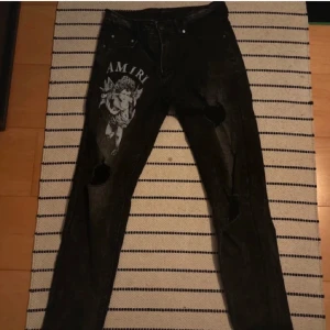 Amiri jeans - Säljer ett par svarta jeans från Amiri med design på låret av cupid och ripped 