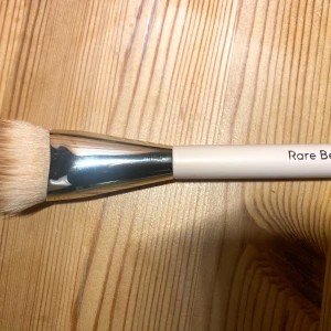 Sminkborste från Rare Beauty - Säljer en blush borste från Rare Beauty. Perfekt för att applicera liquid och powder blush .  Ren och sanerad Tack! 