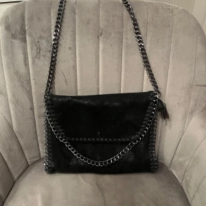 Svart axelväska med kedjedetaljer - Snygg svart axelväska med coola kedjedetaljer och leopardmönstrat foder. I väldigt bra skick, endast använd några gånger. Skriv om ni har frågor💗