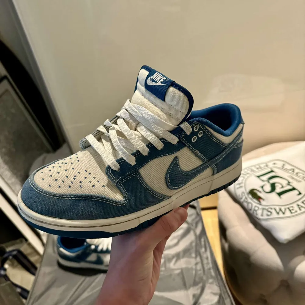 Säljer ett par snygga Nike Dunk sneakers i blått och vitt. De har en cool denim-look med vita snören och en klassisk Nike-logga på sidan. Perfekta för både vardag och fest! Skorna är i okej skick. Skor.