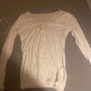 Vit långärmad topp med spetsdetaljer - Säljer en söt vit långärmad topp från intimissimi med vacker spetsdetalj vid halsringningen. Perfekt för vår och sommar! Toppen är i bra skick och passar till både vardag och fest. Aldrig använd, är i storlek M men passar som xs/s 