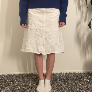 Vit jeans kjol - Säljer en superfin vit jeanskjol. Den har en enkel och stilren design med en normal passform som passar perfekt till både vardag och fest. Kjolen är i mycket bra skick och har en bekväm längd som slutar strax under knäna. Perfekt för vår och sommar!