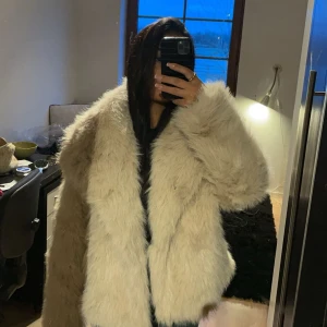 Beige pälsjacka - Säljer en supermysig beige pälsjacka som är perfekt för kalla dagar. Den är fluffig och varm, med en loose passform som gör den bekväm att bära över tjockare tröjor. Jackan har långa ärmar och en stilren design utan krusiduller. Perfekt för både höst och vinter! 