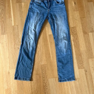 Blå jeans från SMOG - Säljer ett par klassiska blå jeans från SMOG i storlek 30/32. De har en straight passform och är i bra skick med lite slitage för en cool look. Perfekta för vardagsbruk och kan matchas med det mesta. Sköna och stilrena jeans som funkar året runt! Dom är skinny och raka