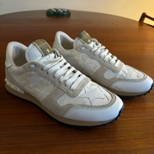 Valentino Rockrunner - Säljer ett par snygga Valentino Rockrunners i mycket bra skick. De är vita med stjärnmönster och har coola nitar på hälen. Skorna har en robust svart sula och är perfekta för både vardag nu när det börjar bli kallare och fest. Storlek 42 men passar mer 43, inget og kommer med tyvärr.