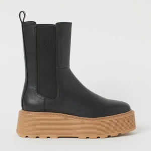 Svarta boots med platåsula - Snygga svartaboots i skinn med en cool platåsula i beige. Perfekta för höst och vinter, dessa boots har en elastisk sida för enkel på- och avtagning. De är både stiliga och bekväma, vilket gör dem till ett måste i garderoben. Passar perfekt till både jeans och klänning! I princip oanvända 