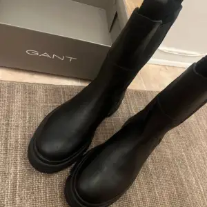 Säljer ett par svarta ankelboots från GANT i modellen MONTHIKE. De är i nytt skick och har en robust sula som ger bra grepp. Perfekta för höst och vinter med sin stilrena design och bekväma passform. Skorna är gjorda i skinn och passar till både vardag och fest.