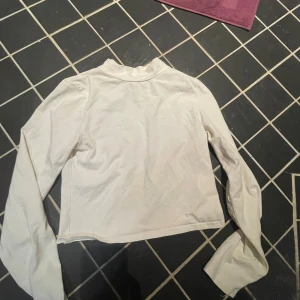 Vit långärmad topp från Bik Bok - Säljer en vit långärmad topp från Bik Bok i storlek M. Den är croppad och har en enkel design som passar perfekt till vardags eller att styla upp för fest. Toppen är i mycket bra skick och gjord av mjukt material för en bekväm passform.
