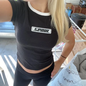 Svart croppad t-shirt - Säljer en svart croppad t-shirt från Seoul med vit kant vid halsen och ett tryck på bröstet. Perfekt för en casual look eller träning. T-shirten är tight och bekväm, passar bra till både jeans och träningsbyxor.