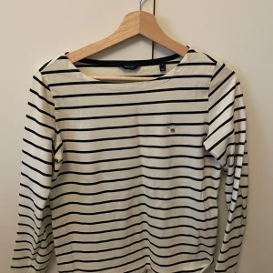 Randig långärmad tröja från GANT - Säljer en klassisk randig tröja från GANT i storlek S. Den är vit med svarta ränder. Tröjan är använd men i mycket bra skick.