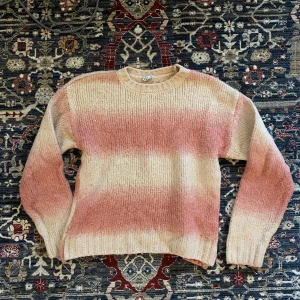Rosa och beige stickad tröja! - Säljer en supermysig stickad tröja i rosa och beige från Cubus. Den har ett randigt mönster och är perfekt för höst och vinter. Tröjan är långärmad och har en klassisk rund halsringning. Perfekt för att hålla sig varm och stilren under kyliga dagar! 🍂 Lite nopprig därav lite lägre pris. 