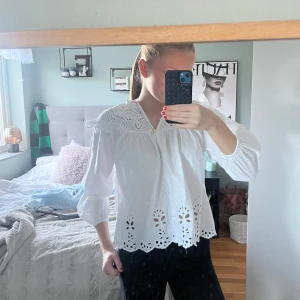 Vit blus med spetsdetaljer - Säljer en superfin vit blus med spetsdetaljer och broderade mönster. Blusen har trekvartsärmar och en lös passform, perfekt för vår och sommar. Den är i mycket bra skick och passar både till vardags och festligare tillfällen. Storlek 152 men passar en S.