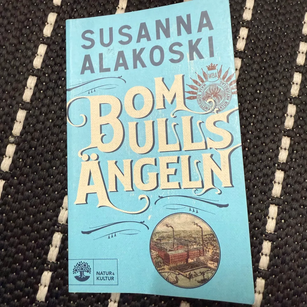 Säljer boken 'Bomullsängeln' av Susanna Alakoski. Den har ett blått omslag med stora vita bokstäver och en illustration av en fabrik. Boken är en del av en historisk romanserie som utforskar kvinnors liv i Finland och Sverige. Perfekt för dig som gillar djupa och gripande berättelser.. Böcker.