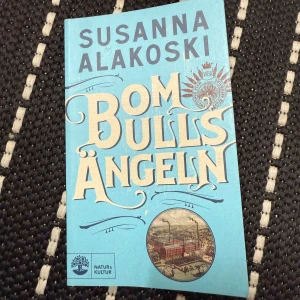 Bomullsängeln av Susanna Alakoski - Säljer boken 'Bomullsängeln' av Susanna Alakoski. Den har ett blått omslag med stora vita bokstäver och en illustration av en fabrik. Boken är en del av en historisk romanserie som utforskar kvinnors liv i Finland och Sverige. Perfekt för dig som gillar djupa och gripande berättelser.