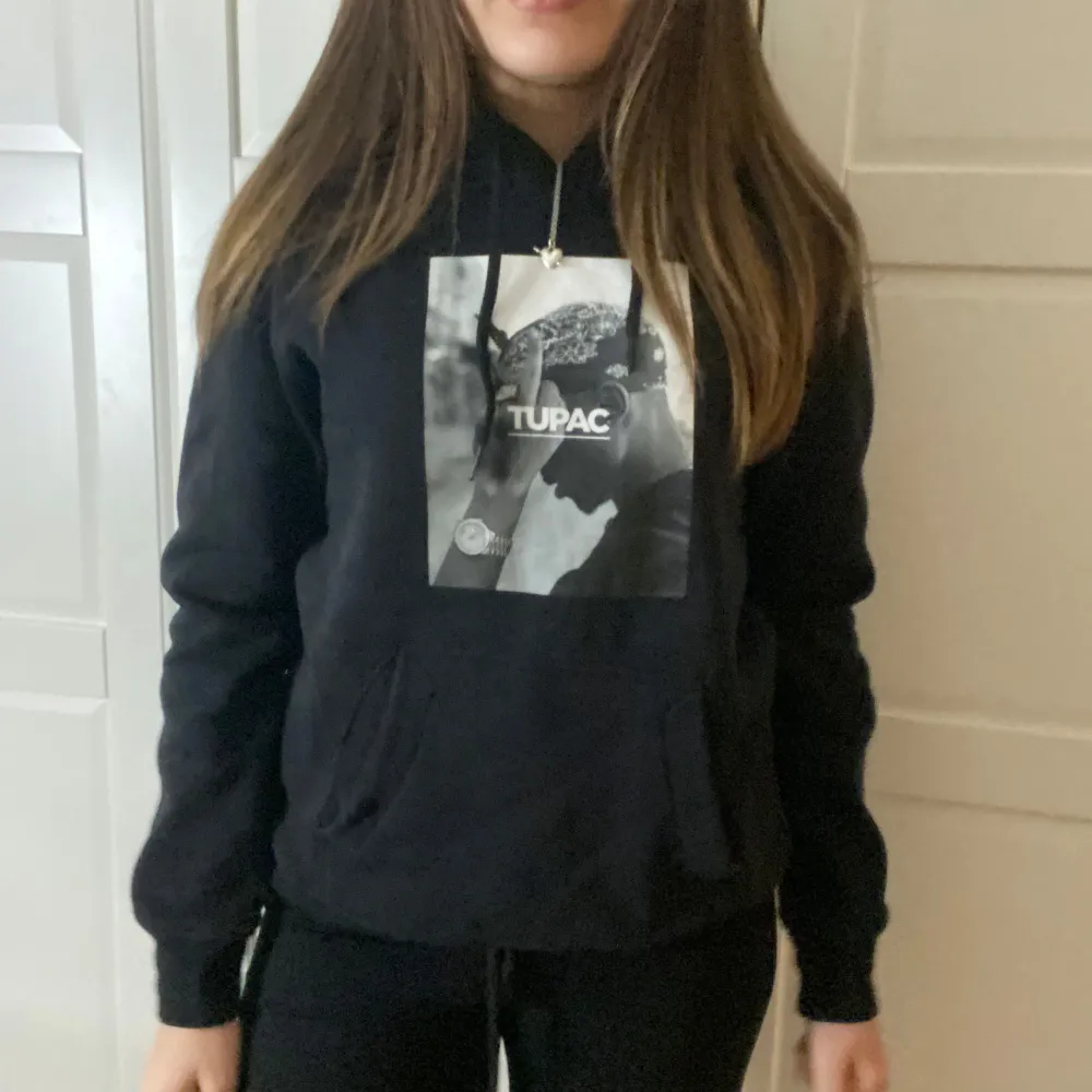 Säljer en svart hoodie med ett coolt Tupac-tryck på framsidan. Den har en klassisk passform med långa ärmar och en bekväm huva med dragsko. Perfekt för vardagsbruk eller när du vill ha en avslappnad stil. Passar bra till jeans eller mjukisbyxor. Den är lite liten i storleken så skulle säga storlek S. Hoodies.