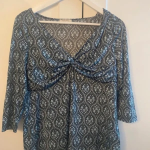 Mönstrad topp från Happy Holly - Säljer en superfin topp från Happy Holly i storlek 36/38. Den har ett mönster i blått/turkost och svart med trekvartsärmar och en v-ringning. I mycket fint skick!