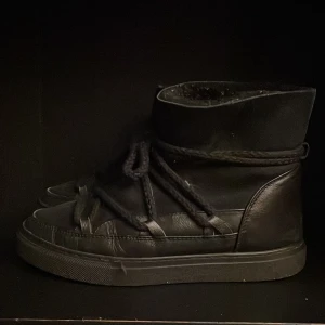 Svarta boots från Inuikii - Säljer ett par svarta boots från Inuikii i skinn. De har en cool design med snörning och en högre skaft. Perfekta för höst och vinter, håller dig varm och stilren. Använda men i bra skick.