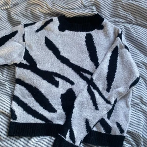 Mönstrad stickad tröja - Säljer en vit och svart stickad tröja med ett ”zebra”-mönster ish. Har använts men ändå inte så sliten, säljer då den inte passar mig längre!