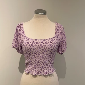 Blommig topp - Superfin lila topp med blommigt mönster. Perfekt för vår och sommar, och funkar både till vardags och fest. Toppen är i mycket bra skick och har en tight passform.🌸
