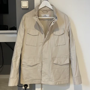 Nästan slutsåld över allt, beige field jacket från John Henric - Säljer en stilren jacka från john henric i storlek Xs men den passar bättre i storlek S. Riktigt fin biege färg och sitter som en smäck. Jackan är i ett väldigt bra skick!!