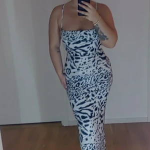 Zebramönstrad långklänning - Snygg zebramönstrad långklänning med smala axelband och öppen rygg. Perfekt för en djärv look. Klänningen har en figurnära passform som framhäver silhuetten.