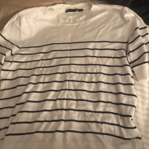 Vit och svart randig tröja från 157 - Säljer en stilren vit tröja med svarta ränder från 157. Tröjan har en klassisk design med rund hals och medellånga ärmar. Perfekt för en avslappnad look. Väldigt skön och säljer för bara har legat i garderoben 