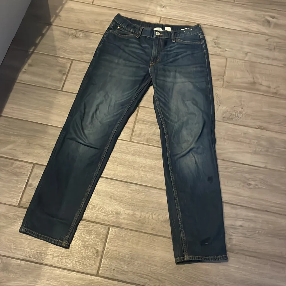 Snygga blå jeans med slim fit och justerbar midja. Perfekta för en stilren look. Klassisk design med fem fickor och knappgylf.. Farkut & Housut.