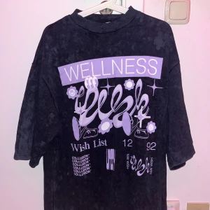 Svart t-shirt med lila tryck - Cool svart t-shirt med lila tryck. Strl 32 MEN den är VÄLDIGT oversized, passa mer som en strl S/M. Jag bär strl XS och säljer pga den är för stor. Endast testad. ≈73 cm i längd (första bilderna är tagen med blixt, därför syns mönstret mer)