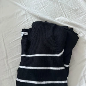 Svart och vit randig tröja från Bubbleroom - Säljer en snygg svart tröja från Bubleroom med vita ränder. Tröjan är ribbad och har långa ärmar, perfekt för en stilren look. Passar bra till både jeans och kjol.
