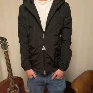 Moncler windbreaker - Säljer en stilren svart windbreaker från Moncler med huva och dragkedja. Jackan har Moncler-logga på ärmen och ränder i rött och vitt på huvan. Nypris 8199 kr! Kvitto finns hör av gärna vid ett bud elle fler frågor 😁