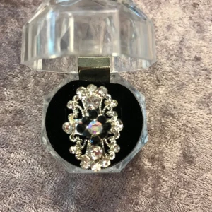 Glittrig ring med kristaller - Elegant ring med gnistrande kristaller i en intrikat design. Perfekt för att ge en touch av glamour till din outfit. Ringen kommer i en stilren, transparent ask.  Justerbar storlek, helt ny . 75kr/st 