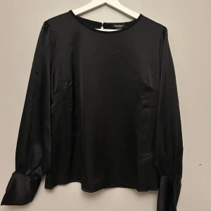 Svart långärmad blus  - Jag säljer en svart långärmad blus i satin-liknade material. Köpt från Boohoo men är aldrig använd. Så fin tröja till både vardag och finare tillställningar 💗