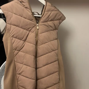 Beige quiltad väst med dragkedja - Snygg beige quiltad väst med dragkedja framtill. Perfekt för lager-på-lager under kyligare dagar. Västen har en modern design och är lätt att matcha med olika outfits.