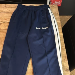 Palm Angels byxor - Sjukt snygga Palm Angels byxor. Säljer pågrund av simpla anledningen att jag växt ur dem som ni ser. passar runt 170-180. inga defekter förutom lite smutsig bara som lätt går bort i tvätten.