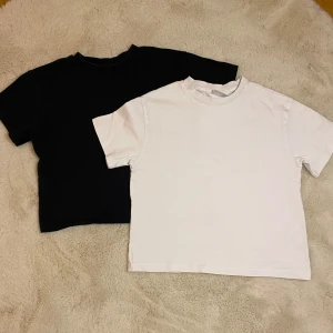 Svart och vit t-shirt från Gina Tricot - Två klassiska t-shirts från Gina Tricot i storlek 146/152. En i svart och en i vit, båda med rund hals och korta ärmar. Perfekta basplagg för alla tillfällen. FRAKT INGÅR INTE i priset