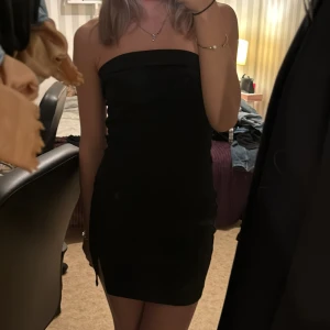 Svart axelbandslös klänning - Snygg svart axelbandslös klänning med en liten slits på sidan. Perfekt för en kväll ute. Enkel och stilren design som passar till många olika tillfällen💕