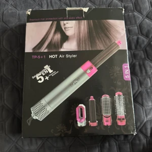 Hot Air Styler 5-i-1 - Säljer en Hot Air Styler 5-i-1 med flera tillbehör för olika stylingbehov. Den har en silver och rosa design med en enkel knapp för att justera inställningarna. Perfekt för att skapa olika frisyrer med ett enda verktyg. Knappen är tejpad pågrund av att den låsnat men funkar som om den inte.💕