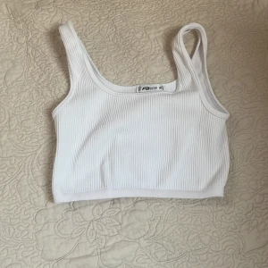 Vit ribbad linnetopp från NewYorker - Säljer en vit ribbad linnetopp från NewYorker i storlek XS. Toppen är ärmlös och har en croppad ärmar och passar bra. Den är tillverkad i ett mjukt och stretchigt material som ger en bekväm känsla.