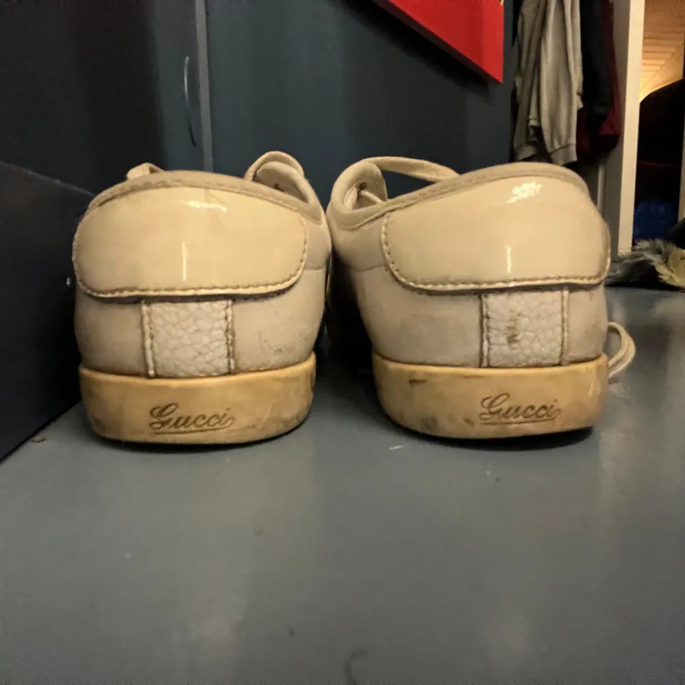 Snygga beige sneakers från Gucci med klassiska ränder i grönt och rött på sidan. Skorna har snörning och är tillverkade i skinn. Perfekta för en stilren look.lite smutsiga men väldigt snygga.. Kengät.