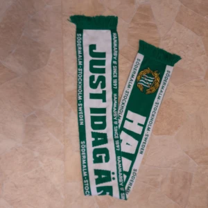 Halsduk Hammarby, Bajen, Just idag är jag stark - Halsduk i grönt och vitt med texten 'JUST IDAG ÄR JAG STARK' och 'HAMMARBY'. Tyvärr noppig efter den blivit tvättad. Ändå bra använt helt acceptabelt skick.