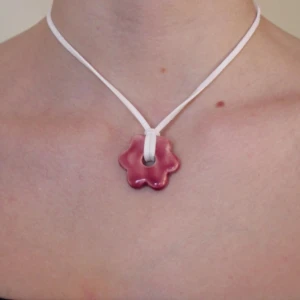 Rosa blomformad halsband - Charmigt halsband med en rosa blomformad berlock på ett vitt band. Handgjort i keramik av oss - Vivid UF. Om annan färg önskas, beställ i Instagram DM. @_vividuf
