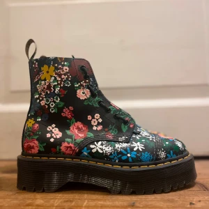 Dr martens  - Dr. Martens i storlek 42 (normal i storleken) Använda vid max 3 tillfällen. Modell och utseende: SINCLAIR DISTORTED PLATTFORMSKÄNGOR – Blommiga kängor, hög sula samt dragkedja med unik snörning. Plattformshöjd: 3,8 cm Material: 	•	Yttre material: 100% Läder 	•	Insida: 60% Läder, 40% Textil Bara att höra av dig om du undrar något!  Kategori: Ankelboots Varumärke: Dr. Martens Storlek: 42 Skick: Ny utan prislapp Material: Läder Färg: Svart, Multi