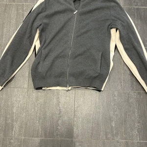 Tröja med dragkedja från Massimo Dutti - Snygg tröja med dragkedja från Massimo Dutti i olika färger: grå, vit och svart. Perfekt för en stilren look. Tröjan har långa ärmar och en enkel design som passar till många tillfällen. Storlek: XL