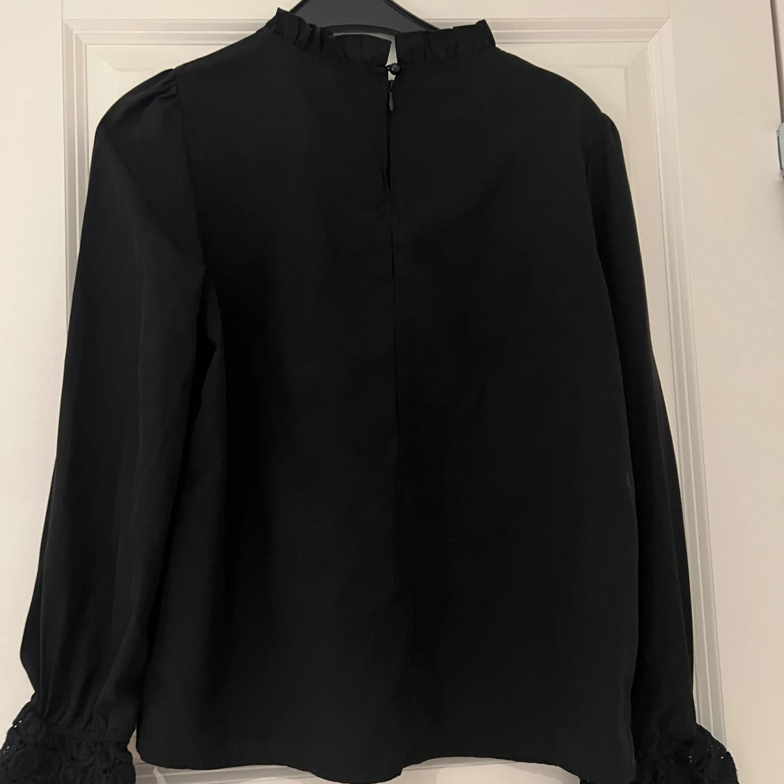 Svart blus med blommig design på armen - 2