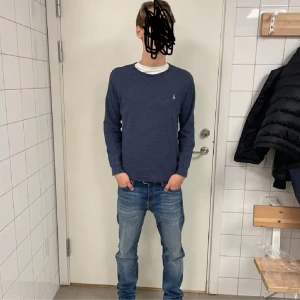 Blå tröja från Ralph Lauren - Säljer en stilren blå tröja från Ralph Lauren med det klassiska broderade logotypen på bröstet. Tröjan har långa ärmar och en rund halsringning. Perfekt för en avslappnad och snygg look.