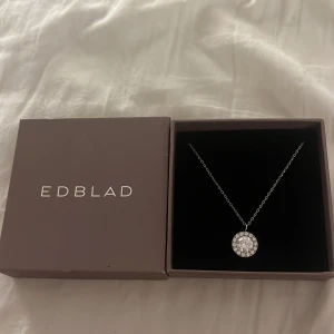 Halsband från Edblad - Elegant halsband från Edblad med en gnistrande rund hängsmycke i stål. Perfekt för att ge en touch av glamour till din outfit. Kedjan är tunn och smidig, vilket gör den bekväm att bära hela dagen. Säljer då jag fick den i silver men jag använder bara guld så det är helt nytt💕