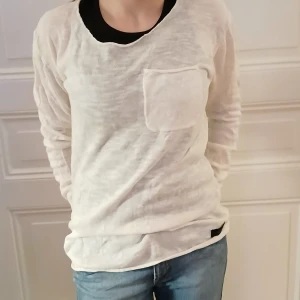 Vit långärmad tröja från Adrian Hammond - Säljer en stilren vit långärmad tröja från Adrian Hammond. Tröjan har en bröstficka och en kontrasterande svart krage. Perfekt för en avslappnad look❤️. Är lite genomskinlig. 